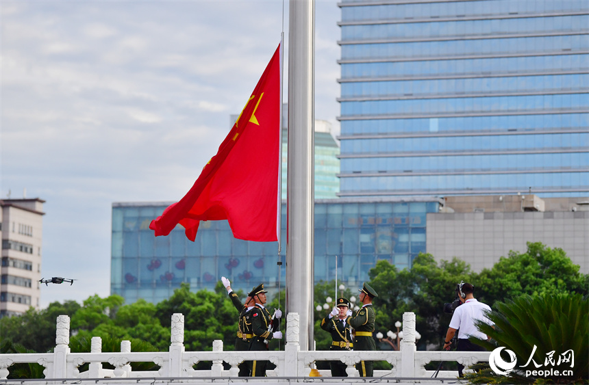 升旗手迎风振臂，将国旗抛向天空。人民网记者 时雨摄