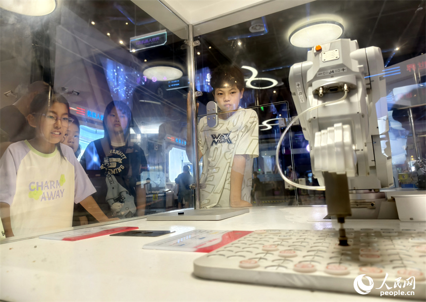 科技馆内，学生们正在围观机器人下象棋。人民网记者 时雨摄