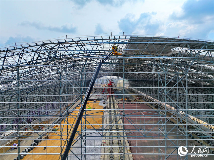 建设者们冒着高温在高空进行货棚挡板安装作业。人民网 朱海鹏摄