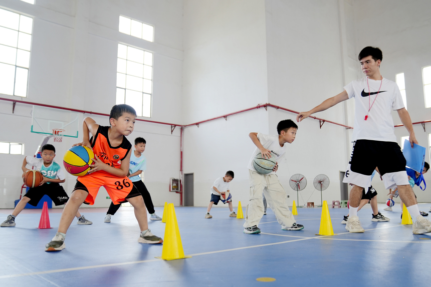 孩子们正在老师的指导下练习篮球基本功。陈旗海摄