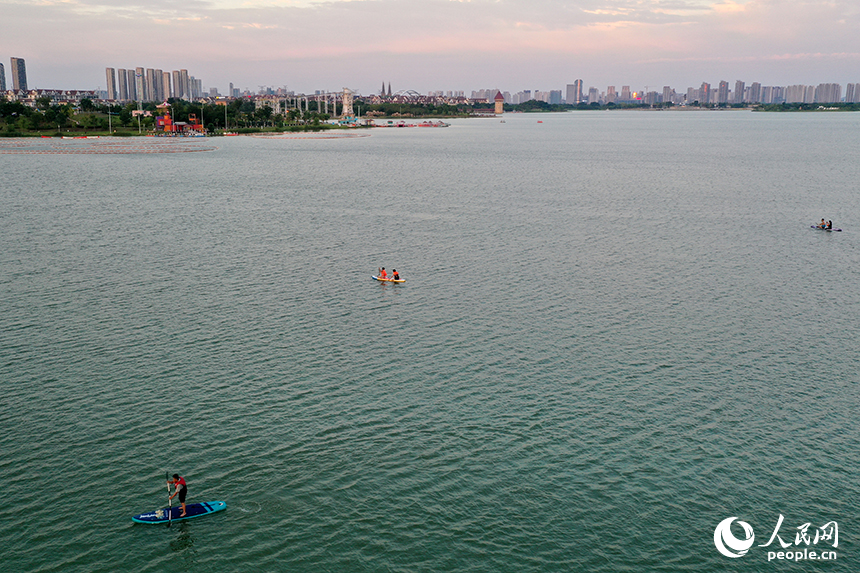 夕阳下，红谷滩区九龙湖泛着金色波光，桨板爱好者们正在湖面挥桨划行。人民网记者 时雨摄