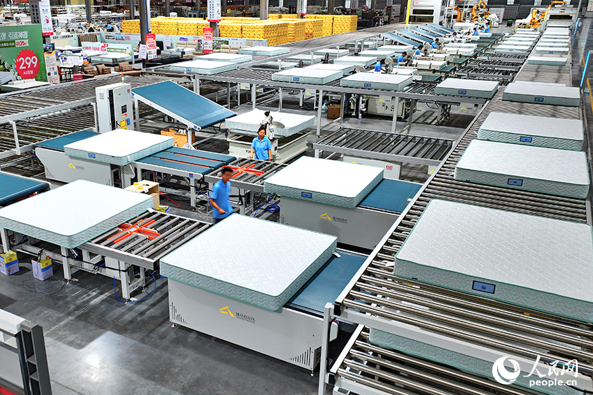 赣州市南康区的A家家居数字化智能制造基地，机械臂、传输机循环作业，工人在智能床垫生产线上赶制订单产品。人民网 朱海鹏摄