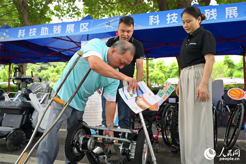 残障人士在科技助残展区咨询试用智能电动轮椅产品。人民网 朱海鹏摄