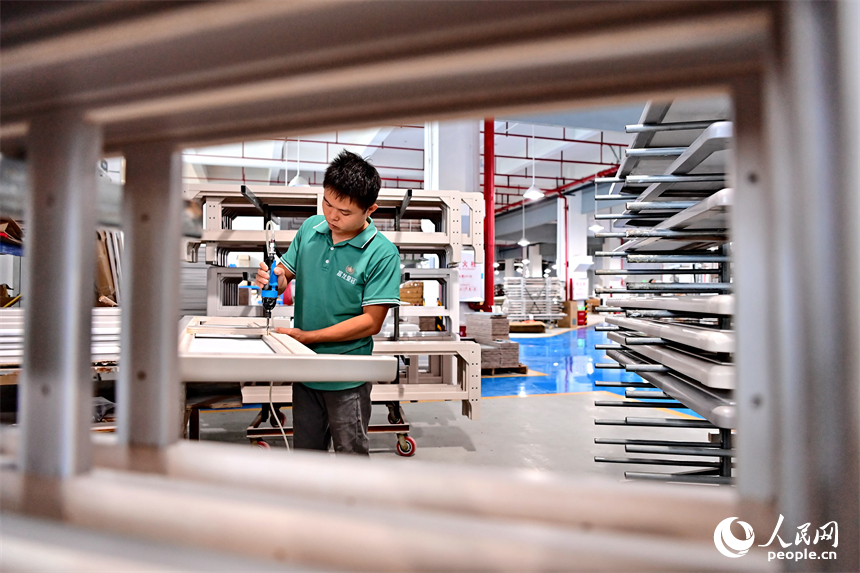 贛州市南康區的一家“工業上樓”項目家具生產企業內，工人在加工軟體家具。人民網 朱海鵬攝