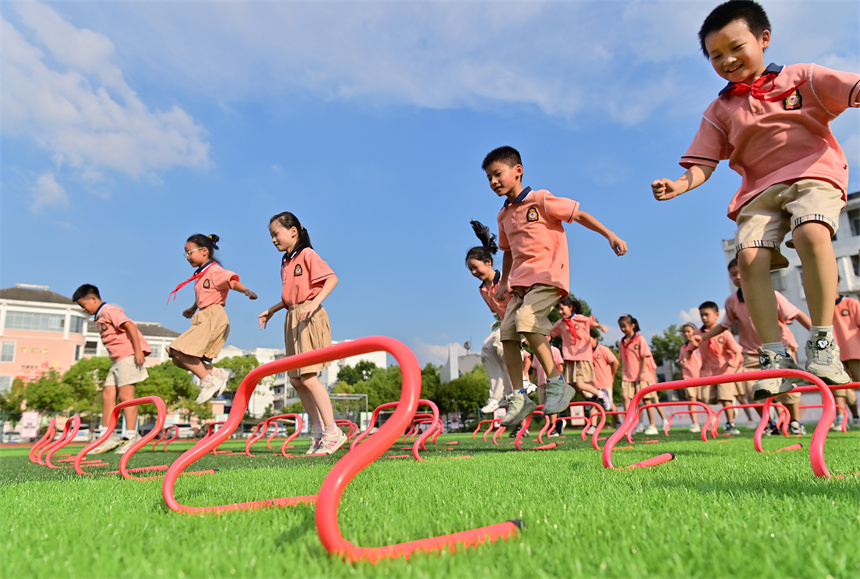 操场上，学生们在参加跨越障碍栏活动。邓龙华摄