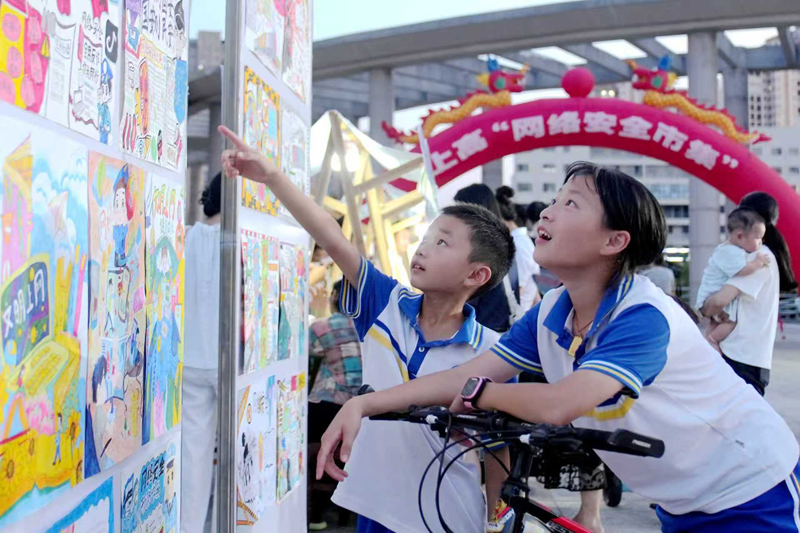 兩名學生正在觀看中小學生繪制的“網絡安全”手抄報。