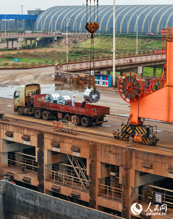 在姚湾综合码头，运输货物的车辆往来穿梭，起重机装卸作业有序进行。人民网 朱海鹏摄