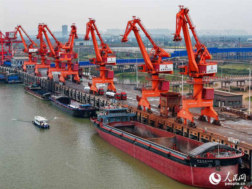 在姚灣綜合碼頭，運輸貨物的車輛往來穿梭，起重機裝卸作業有序進行。人民網 朱海鵬攝