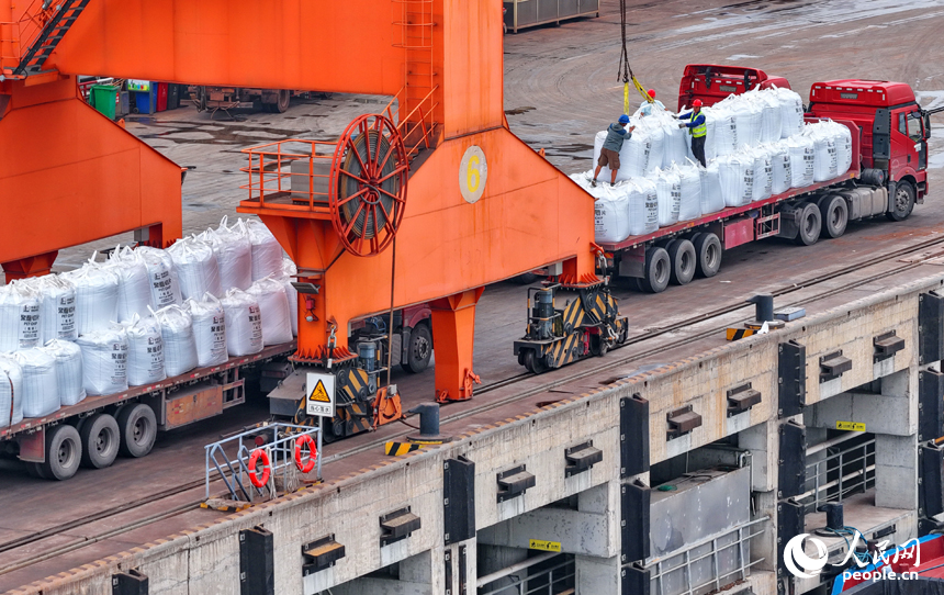 在姚湾综合码头，运输货物的车辆往来穿梭，起重机装卸作业有序进行。人民网 朱海鹏摄