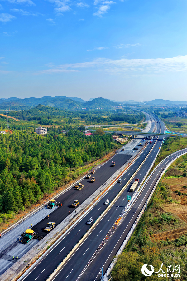 滬昆高速昌傅至金魚石（贛湘界）段改擴建項目施工現場機械轟鳴，工人在攤鋪路面瀝青。人民網記者 朱海鵬攝