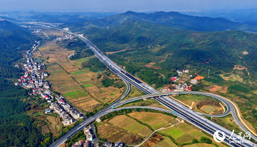 滬昆高速昌傅至金魚石（贛湘界）段改擴建項目施工現場機械轟鳴，工人在攤鋪路面瀝青。人民網記者 朱海鵬攝