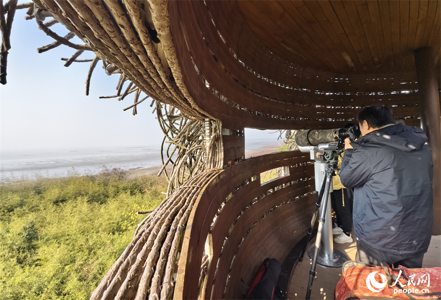 一名摄影师在观鸟点拍摄湖中的候鸟。人民网记者 时雨摄