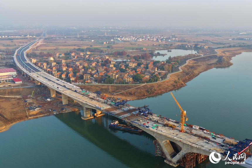 南昌市昌南大橋項目施工現場，吊裝設備來回作業，最后兩段中跨鋼箱梁成功合龍，收尾施工有序進行。人民網記者 朱海鵬攝