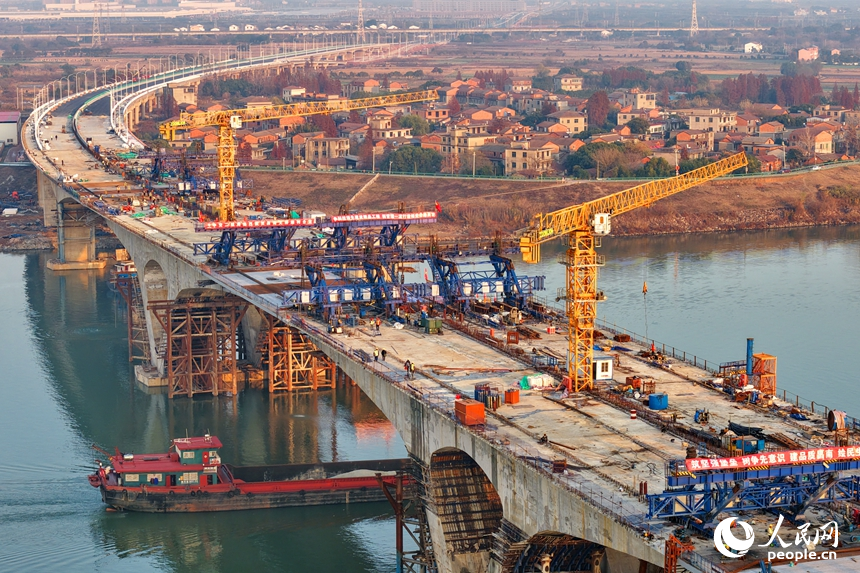 南昌市昌南大橋項目施工現場，吊裝設備來回作業，最后兩段中跨鋼箱梁成功合龍，收尾施工有序進行。人民網記者 朱海鵬攝