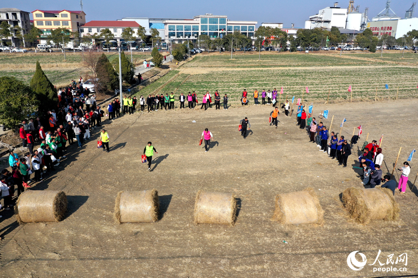 田间趣味活动中，村民在田间运粮接力障碍赛中抱着米袋疾步如飞。人民网记者 时雨摄