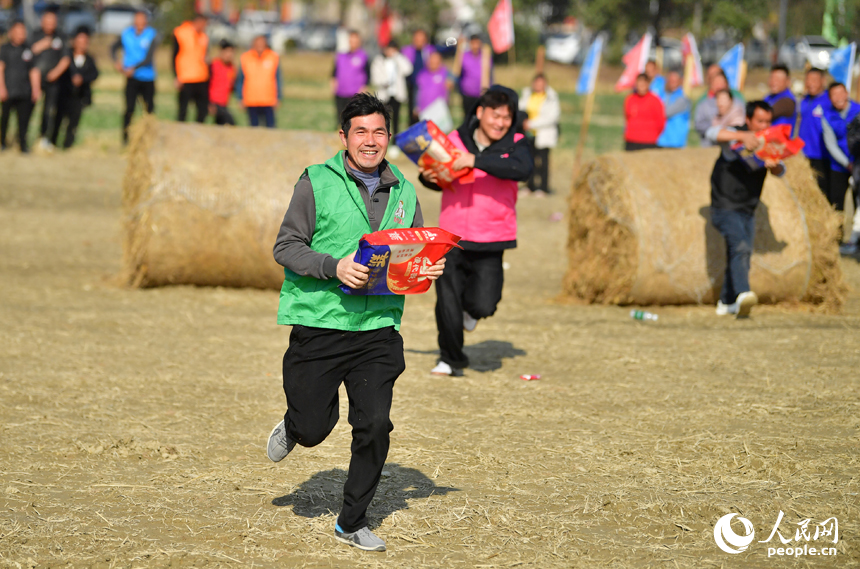 田间趣味活动中，村民在田间运粮接力障碍赛中抱着米袋疾步如飞。人民网记者 时雨摄