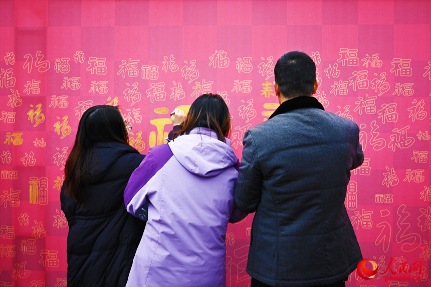 市民游客在“马上有福”纳福墙前挥毫写“福”。人民网记者 黄睿靖摄