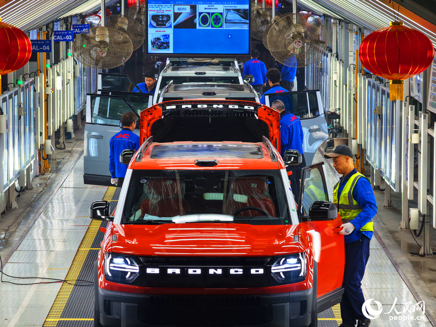 總裝車間內挂上了燈籠，技術人員正在對車身進行下線前的檢測。人民網記者 毛思遠攝