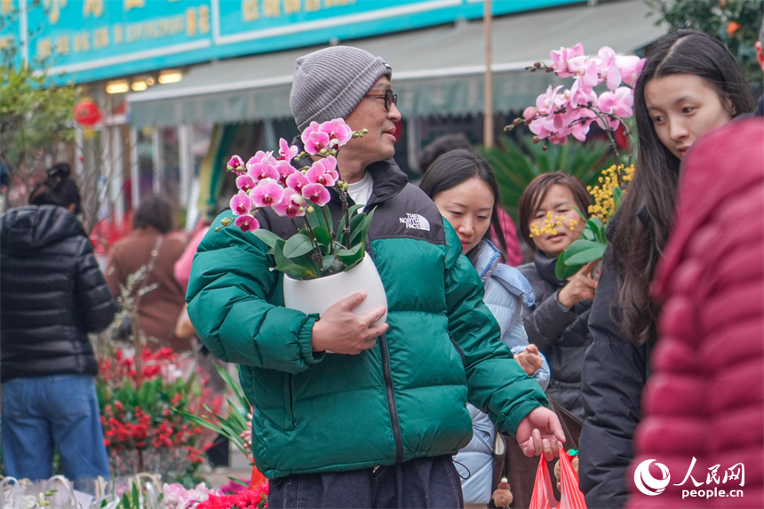 市民手捧心仪年花，满载新春美好期许。 人民网 涂诗轩摄