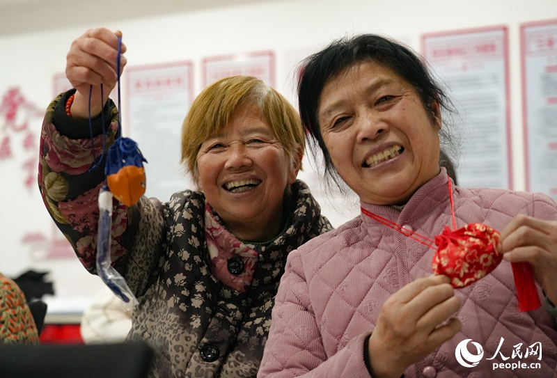 江西省樟树市鹿江街道边街社区内的独居老人与孩子们制作新春香囊。人民网 黄睿靖摄