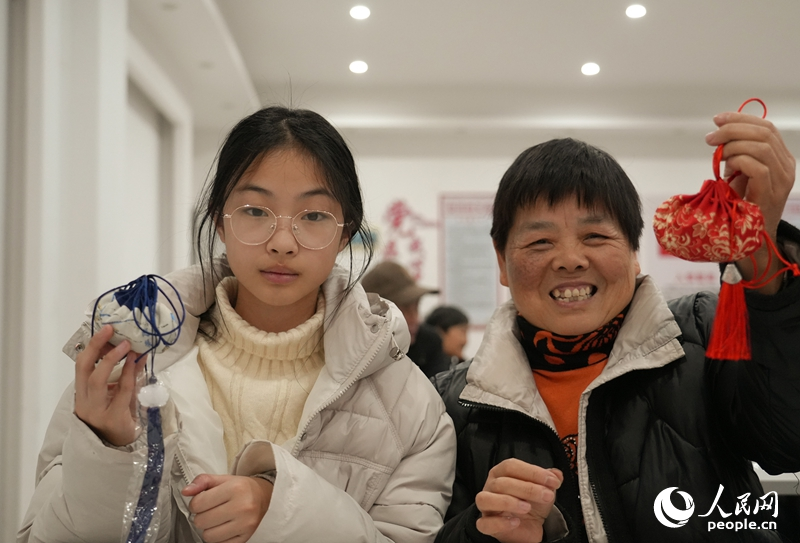 江西省樟树市鹿江街道边街社区内的独居老人与孩子们制作新春香囊。人民网 黄睿靖摄