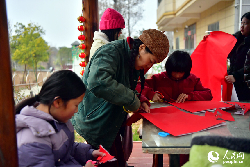 村民与孩童们兴致盎然地剪制窗花。人民网记者 时雨摄