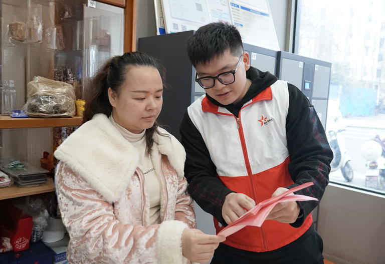 图为烟草普法人员给店家进行普法宣传。张裔昕摄