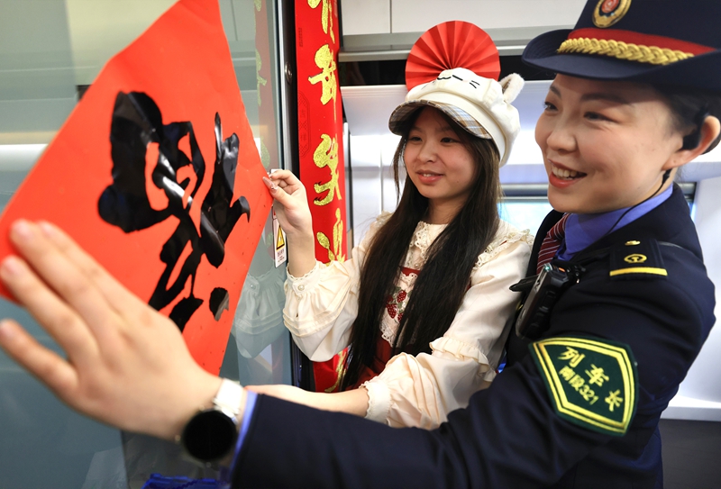 图为列车工作人员与旅客一起贴“福”字。王超摄
