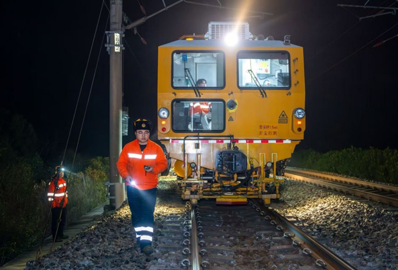 圖為作業人員指揮大型養路機械作業。張萌飛攝