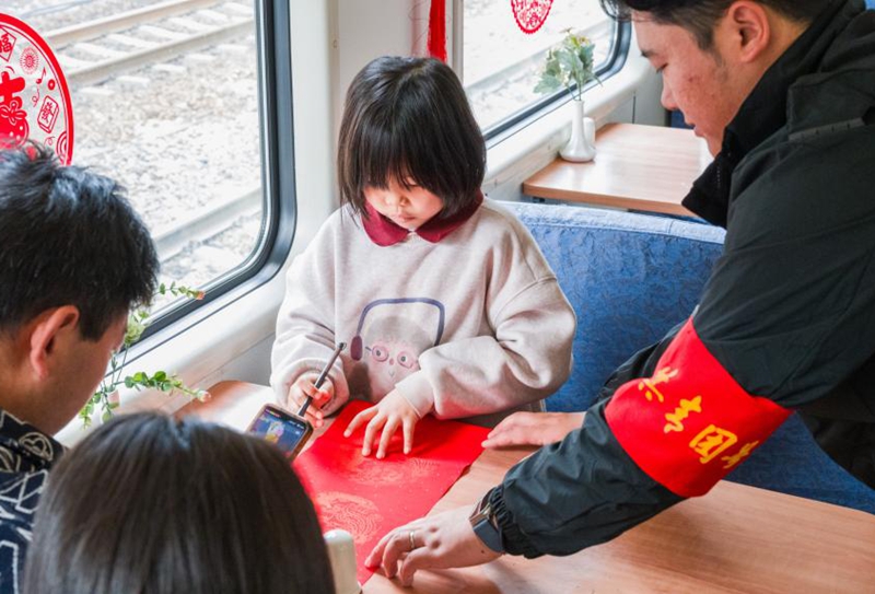 圖為青年乘務員陪伴小朋友手寫春聯迎新年。朱仕煒攝