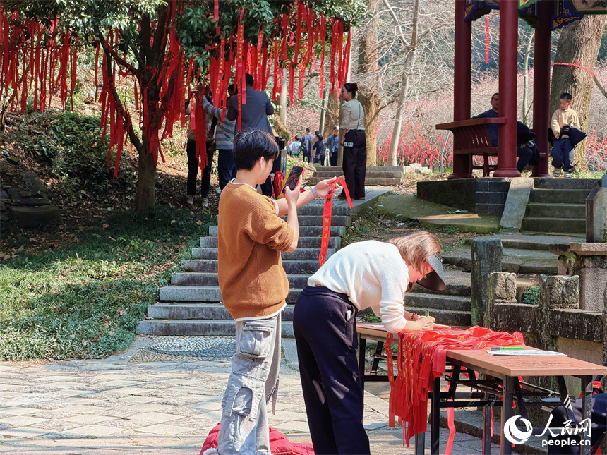 游客在祈福带上写下心愿，寄托美好期许。人民网 孟凡卓摄