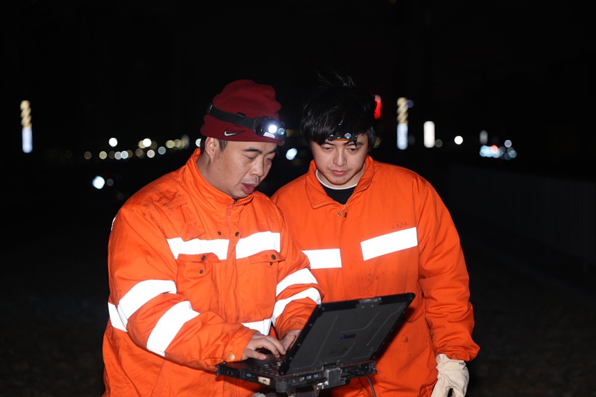 线路工在核对轨面数据。许世东摄