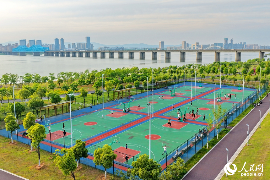 南昌縣象湖濱江江灘體育公園內，市民在健身鍛煉、踢足球、打籃球。人民網記者 朱海鵬攝