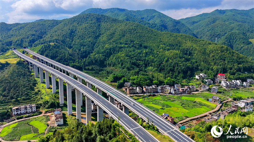 遂大高速公路江西省赣州市上犹县梅水乡园村大桥段，车辆往来驰骋，与村庄民居、群山绿树相映成景。人民网记者 朱海鹏摄