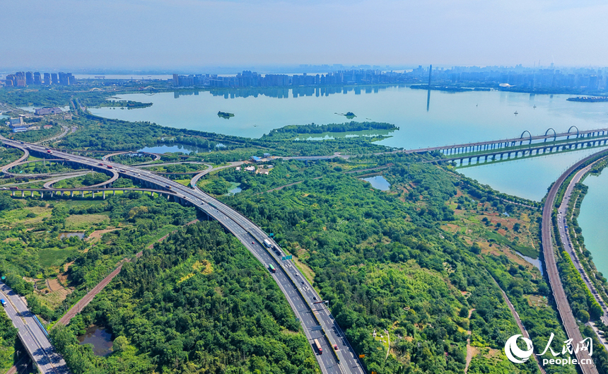 九江市八里湖新区，高速公路、城际高铁、城市道路和环湖公路等交通通道如银龙穿翠纵横交错，与河湖、草木、房屋相映成趣，构成一幅路畅景美的夏日山水城乡画卷。人民网记者 朱海鹏摄