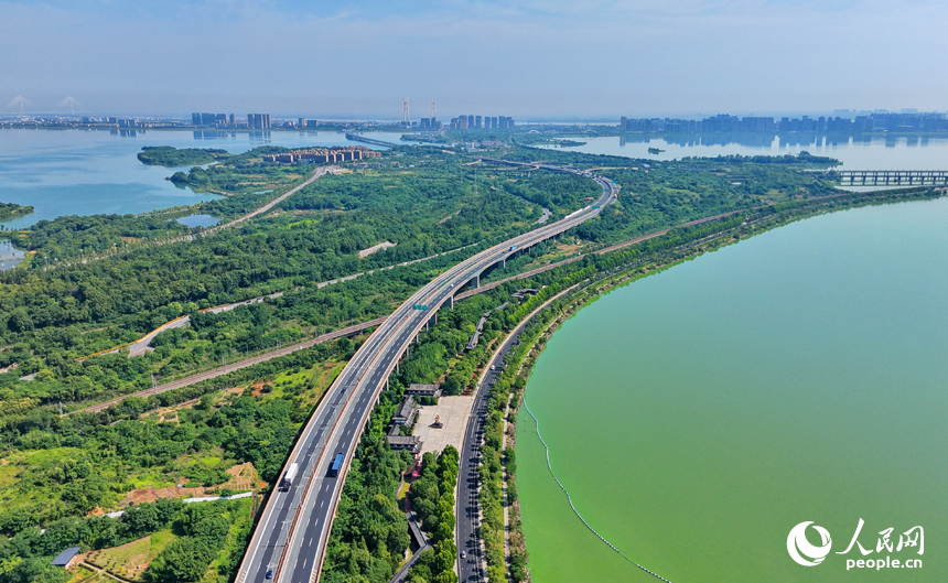九江市八里湖新区，高速公路、城际高铁、城市道路和环湖公路等交通通道如银龙穿翠纵横交错，与河湖、草木、房屋相映成趣，构成一幅路畅景美的夏日山水城乡画卷。人民网记者 朱海鹏摄