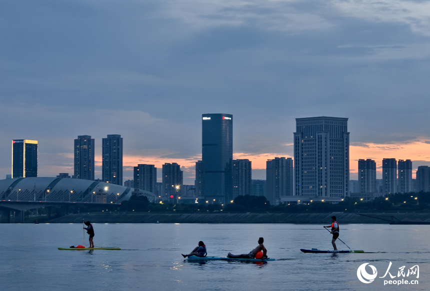 夕阳下，桨板爱好者们挥动桨板放松身心。人民网记者 时雨摄