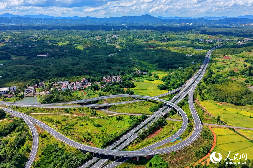 信丰县西牛镇上彭村，穿村而过的南龙高速公路与鳞次栉比的房屋、绿意盎然的田园相互映衬，构成一幅盛夏时节路畅景美的乡村画卷。人民网记者 朱海鹏