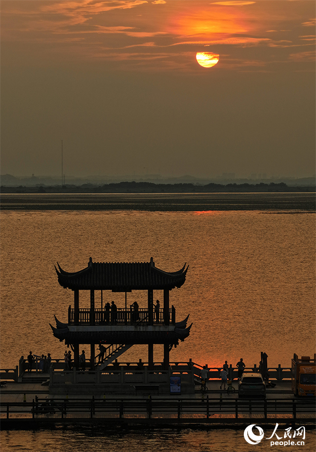 夕阳西下，金色余晖洒满湖面，远处的望湖亭剪影与粼粼波光相映成趣。人民网记者 时雨摄