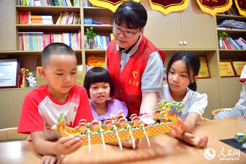 志愿者点评孩子们做的手工作品。人民网记者 时雨摄