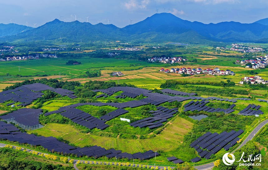 九江市湖口縣武山鎮王常村，連片的光伏發電板分布在林間空地上，與村庄沃野、山巒田疇交相輝映。人民網記者 朱海鵬攝