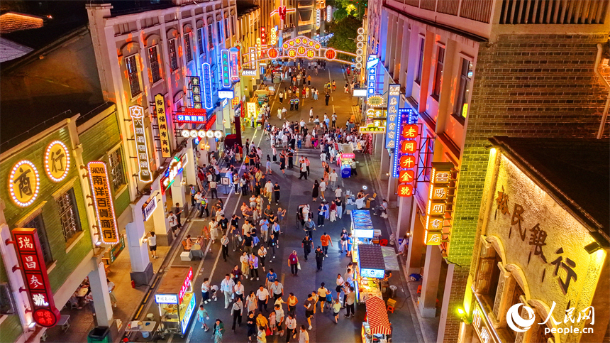 赣州市城区阳明路标准钟夜市街灯火璀璨，游客漫步老街，挑选文创手作，品尝特色小吃、观看非遗展演，畅享夜间消费休闲时光。人民网记者 朱海鹏摄