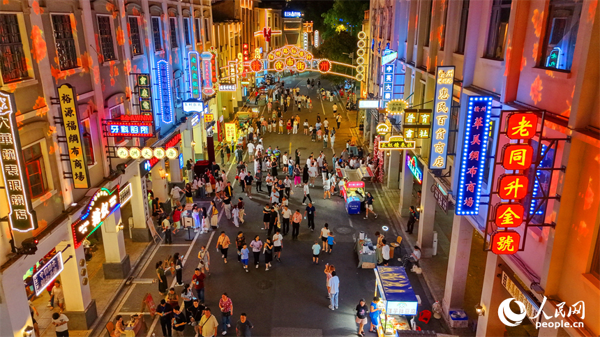 赣州市城区阳明路标准钟夜市街灯火璀璨，游客漫步老街，挑选文创手作，品尝特色小吃、观看非遗展演，畅享夜间消费休闲时光。人民网记者 朱海鹏摄