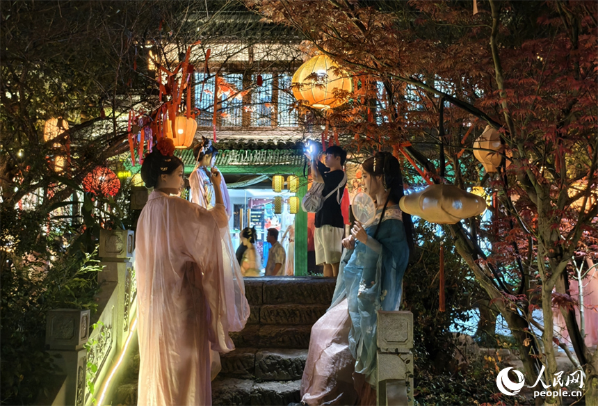 古村夜景迷人，游客们拍照打卡。人民网记者 时雨摄