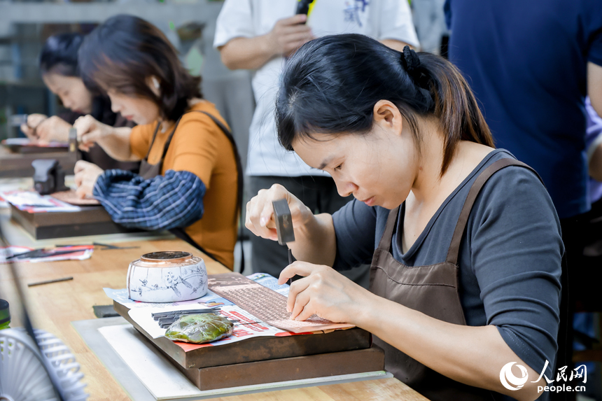 年輕工匠們在銅板上鏨刻。人民網記者 時雨攝